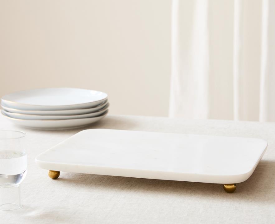 A white marble tray with gold handles and intricate veining patterns