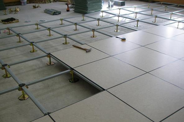 Raised floor installation in progress, showing metal support structures and panels being laid out in a commercial building